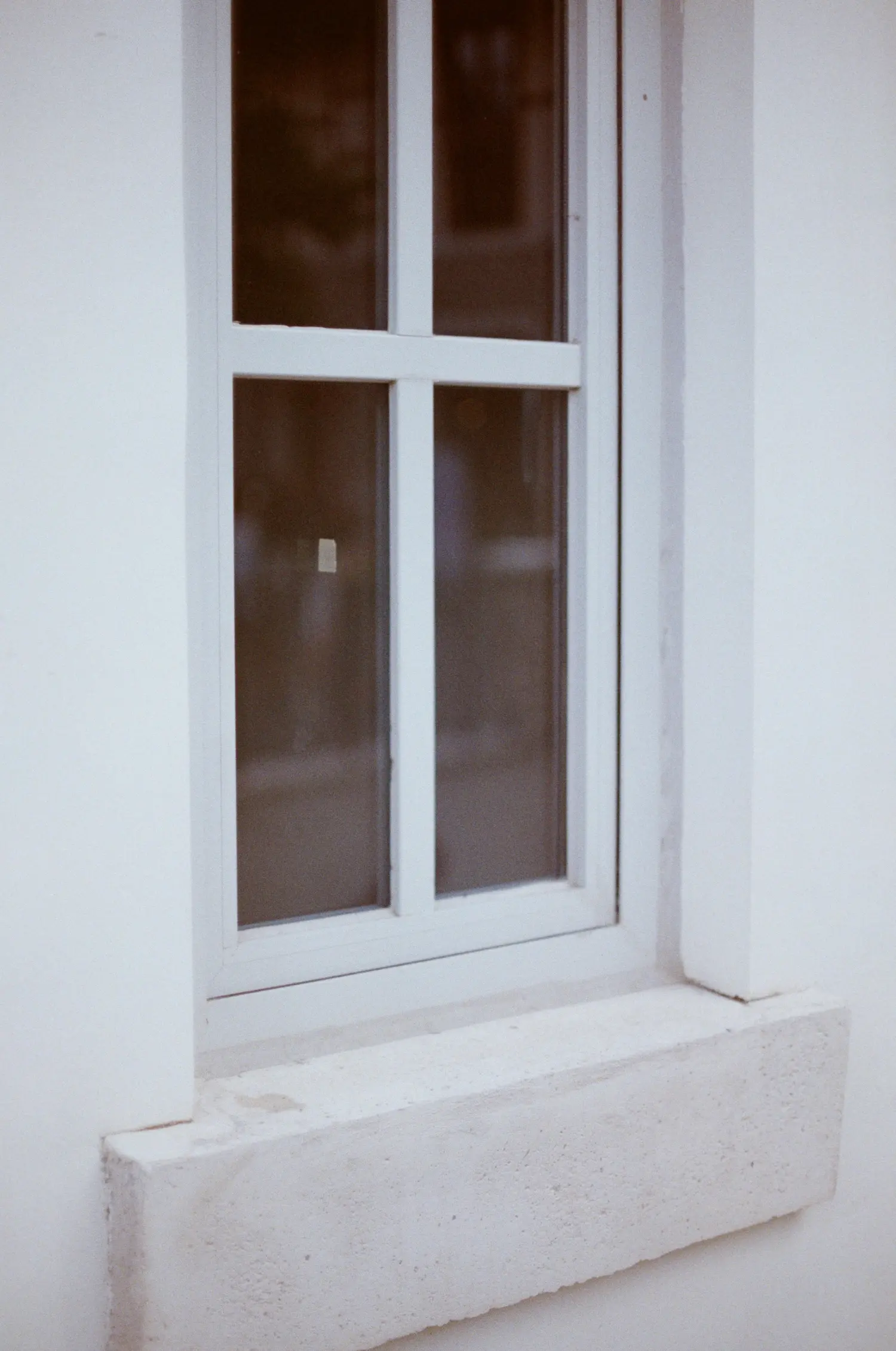 Weißes Kunststofffenster mit Sprossen an einer hell verputzten Fassade