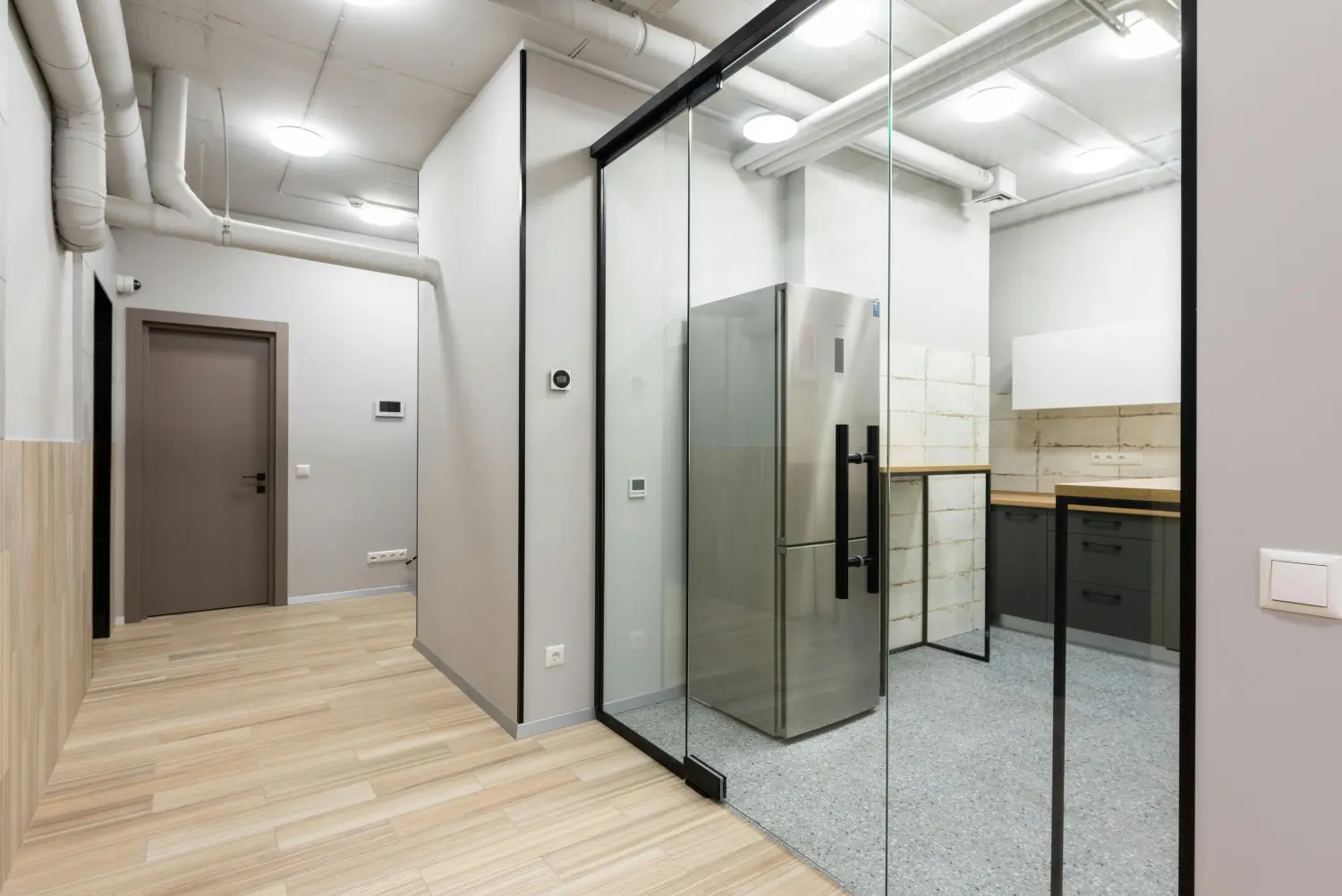 Moderne Ganzglasanlage als transparente Trennwand zwischen Wohnbereich und Küche.